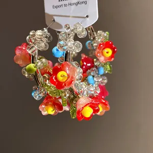 Detailed shot of colorful beaded flower hoop earrings featuring glass charms and silver needles
