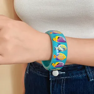 Wide turquoise resin bangle with vibrant tropical fish print worn on wrist detail