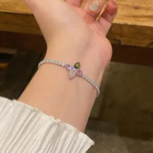 Elegant detail view of a dainty multicolor zircon flower tennis bracelet on a female wrist