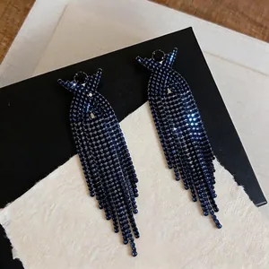Primo piano di orecchini a nappina in strass blu navy con design a croce a X scintillante