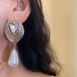 Dettaglio di orecchino a goccia con perla, cristallo sfaccettato e metallo argento.