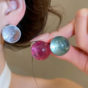 Close-up of translucent resin ball earrings in vibrant colors on a model's ear