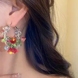 Close-up detail of forest style floral glass beaded hoop earring worn by a model