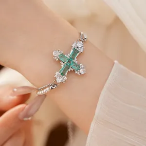 Elegant silver-toned cross bracelet with green zircon and pearls on wrist