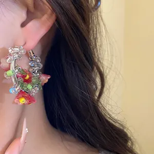 Close-up detail of a Mori style handmade glass beaded flower hoop earring worn on an ear