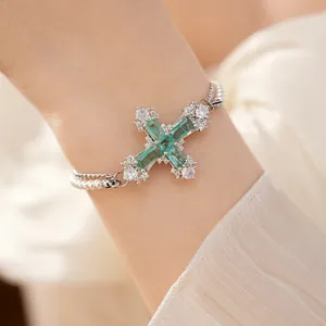 Luxurious emerald-green cross bracelet with pearls and zircon stones on a wrist detail