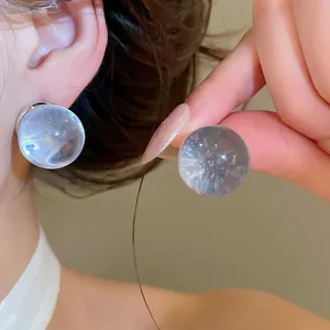 Close-up macro view of clear resin sphere earrings with an icy transparent finish