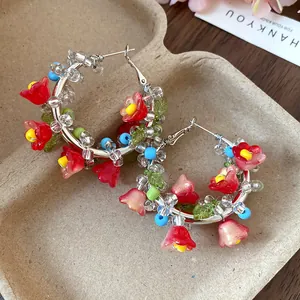 Detailed shot of handmade forest-style hoop earrings with red glass flower beads