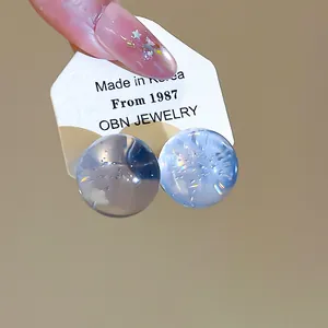 Close-up of ice-clear blue and white resin ball stud earrings with S925 silver needles