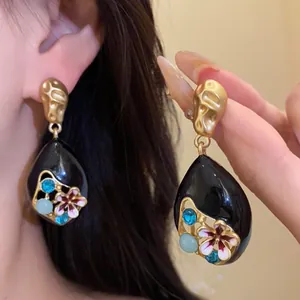 Primo piano di orecchini vintage a goccia neri con fiori smaltati e cristalli blu