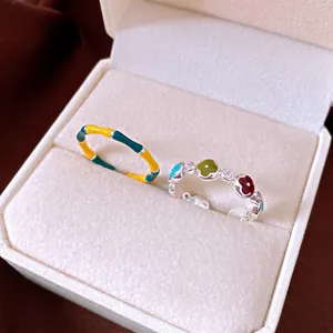 Due anelli a fiore in smalto colorato presentati in un'elegante scatola regalo bianca