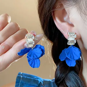 Primer plano detallado de pendientes de pétalos de acrílico azul Klein con circonitas