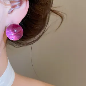 Macro detail of a magenta translucent resin ball stud earring with silver needle pin