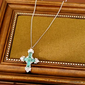 Detail showing vintage cross necklace with green zircon stones on fabric background