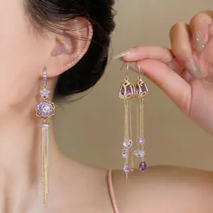 Detail of tulip zircon tassel earrings with elegant gold plating and purple stones