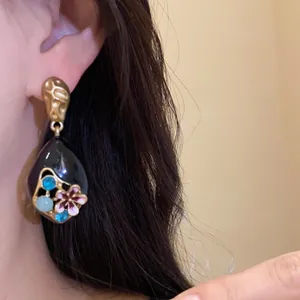 Dettaglio di un orecchino vintage in smalto con fiori colorati e strass scintillanti