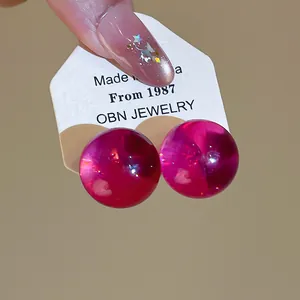 Close-up of translucent pink resin ball stud earrings on a white OBN JEWELRY display card.