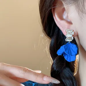 Detalle de pendientes de pétalos de acrílico azul Klein con circonitas en la modelo