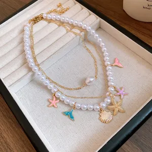 Dettaglio della collana di perle a più strati con ciondoli a forma di stella marina e sirena
