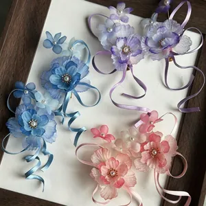 Detailed view of chiffon flower hair clips in pink, blue, and purple on a white background