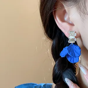 Primer plano de pendientes de pétalos azul Klein con circonitas puestos