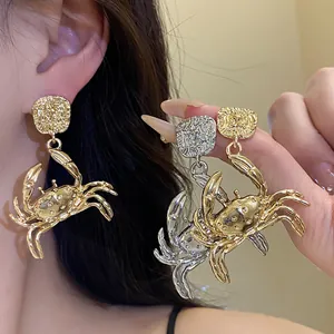 Detailed macro view showing the textured metal craft of gold and silver crab drop earrings