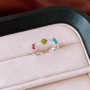 Vista dettagliata di un anello aperto color argento decorato con fiori in smalto e piccole pietre