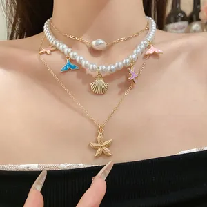 Dettaglio della collana di perle a più strati con ciondoli a stella marina e balena