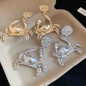 Detailed close-up showing gold and silver metal crab pendant earrings on a tray