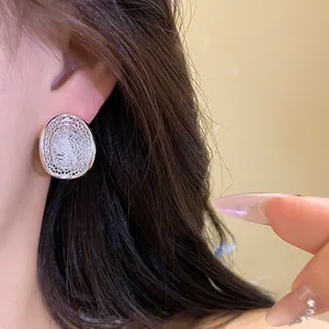 Detailed shot of hollow oval mesh stud earrings with sparkling rhinestones on ear
