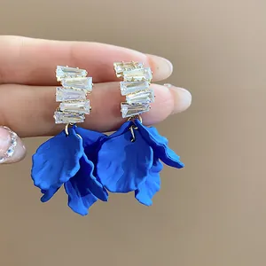 Primer plano de pendientes de pétalos de acrílico azul con circonitas.