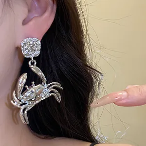 Detailed close-up of a stylish silver metal crab pendant earring worn on the ear