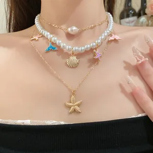Dettaglio di una collana di perle multistrato con ciondoli a stella marina e coda di pesce