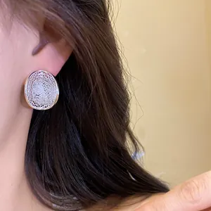 Elegant close-up of silver hollow lattice oval stud earrings with pavé rhinestones