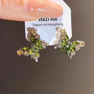 Boucles d'oreilles papillon vertes étincelantes avec zircons sur aiguille en argent.