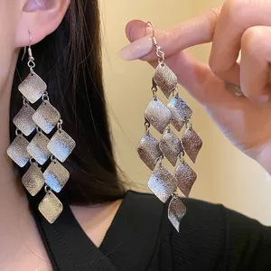 Detailed view of silver matte metal rhombus tassel earrings with tiered geometric design