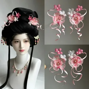 Close-up of pink chiffon flower hair clips with elegant satin ribbons and pearl tassels.