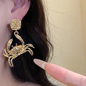 Close-up of golden crab dangle earrings showing intricate metal texture on a model