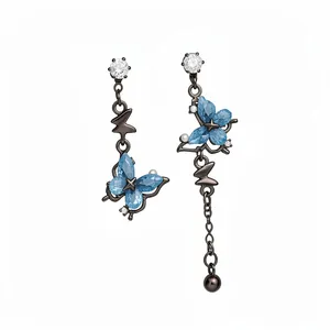 Boucles d'oreilles papillon asymétriques avec cristaux bleus et pompons