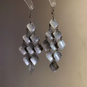 Close-up of vintage matte metal rhombus tassel dangle earrings for stylish women.