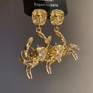 Detailed macro shot of gold metal crab pendant earrings with intricate textures