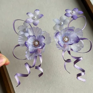 Detail of elegant purple chiffon flower hair clips with long satin ribbons and pearl center.