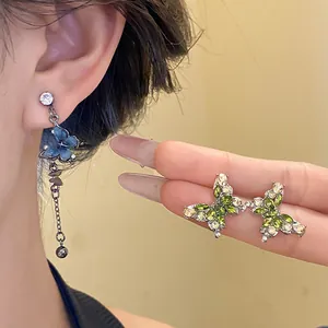 Vue détaillée d'élégantes boucles d'oreilles papillon vertes et bleues avec zircons