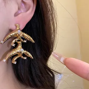 Elegant vintage gold bird drop earrings with pearls and crystals worn on a model.