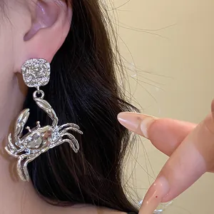 Close-up of stylish silver-tone metal crab pendant earring with textured details