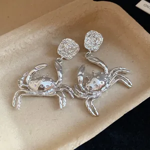 Detailed close-up of silver-toned crab dangle earrings with a unique textured metal finish