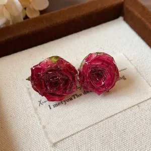 Detailed macro view of handmade real rosebud stud earrings with sterling silver pins