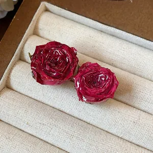 Close-up view of elegant handmade real rose stud earrings with a glossy resin finish