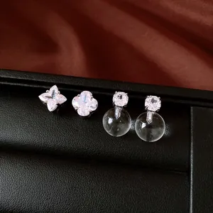 Macro detail of asymmetric silver clover earrings and clear sphere cubic zirconia studs