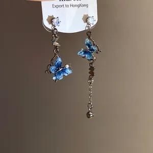 Détail de boucles d'oreilles papillon asymétriques avec zircon et résine bleue